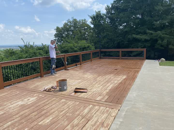Worker applying stain to the deck