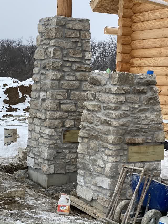Stone pillars on the log home in the snow