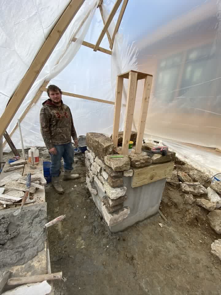 Stone pillar being built inside a heated winter tent