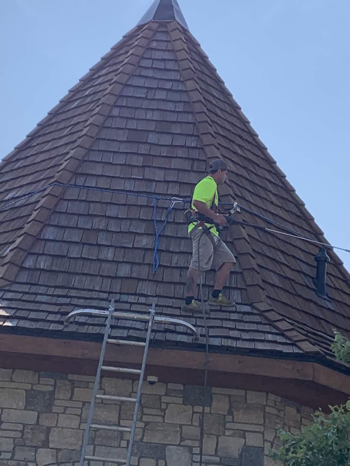Roofer working on the steep turret roof with safety ropes