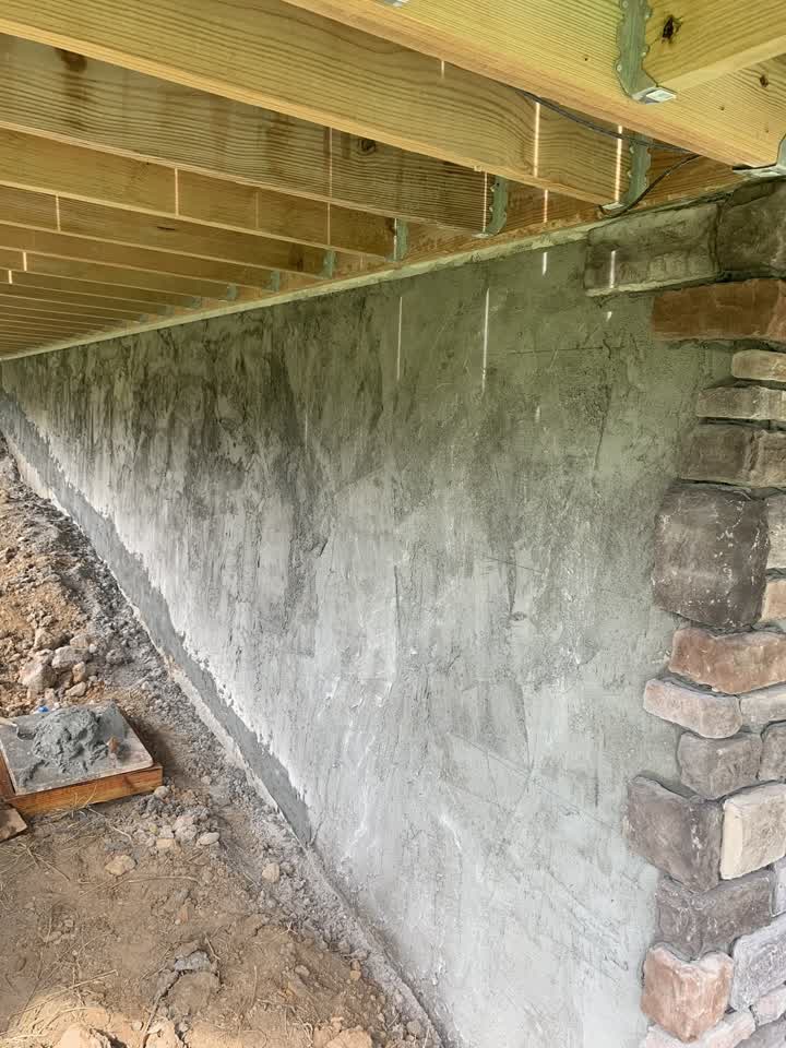 Parged foundation wall under the deck before stone