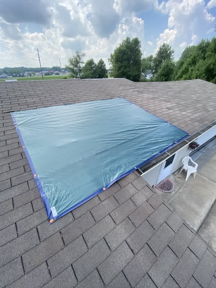 Blue tarp secured over a damaged roof section
